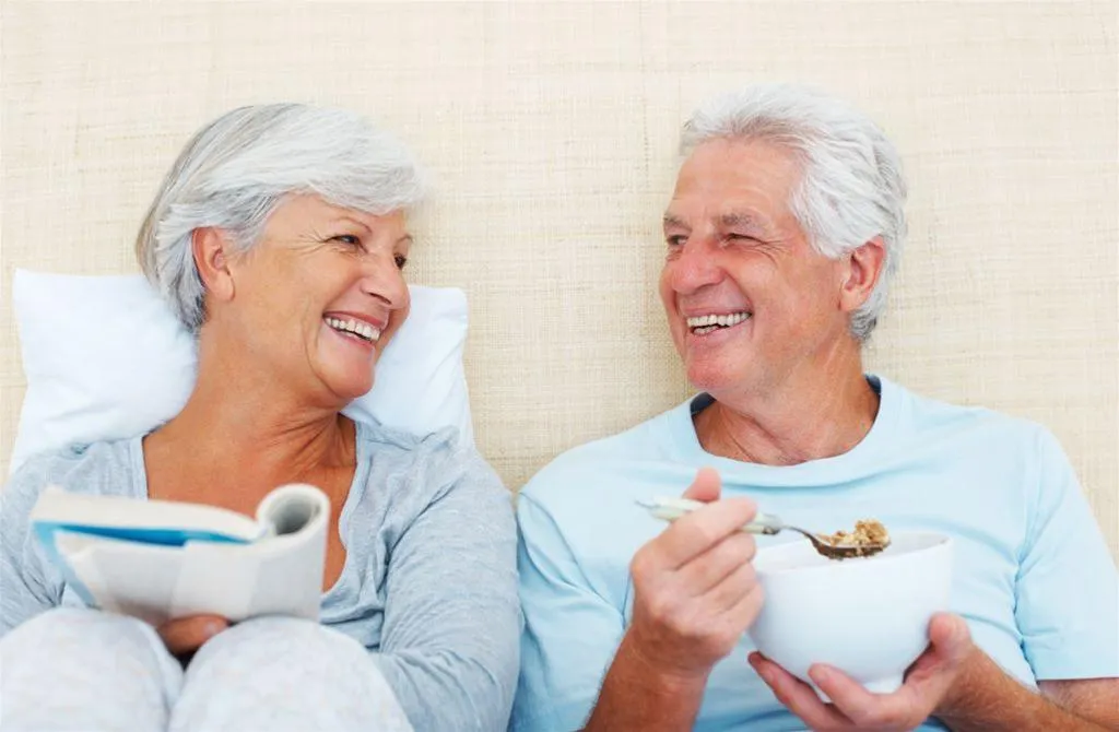 happy older couple reading and eating breakfast